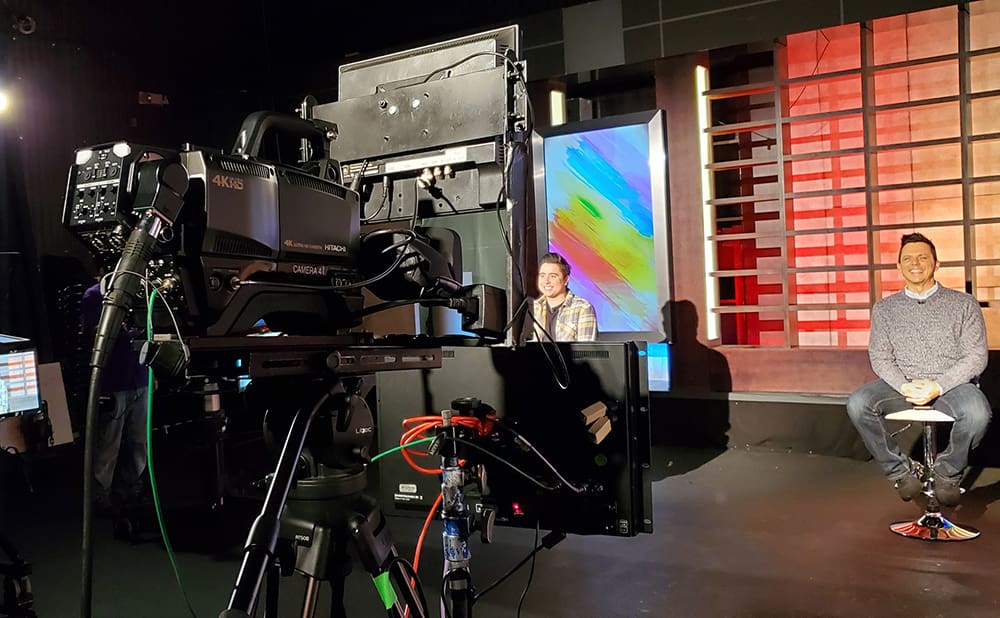 A television set with a man sitting in front of it.